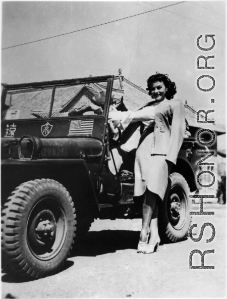 Paulette Goddard hanging onto a Y-force jeep, during WWII.