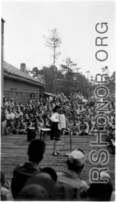 Celebrities (including here apparently Ruth Dennis) perform on an outdoor stage set up at the "Last Resort" at Yangkai, Yunnan province, during WWII. Notice both Americans and Chinese in the audience for this USO event.