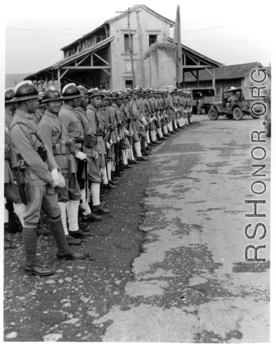 Burma Road dedication parade and ceremony in Kunming, China, on or around February 4, 1945, during WWII. Review of first convoy (or one of the first convoys) to reach China. Chinese soldiers marching in fancy parade dress during, waiting for their turn in the parade.