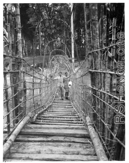 Men, likely Indian soldiers, on a vine and branch bridge in Burma or India.  Near the 797th Engineer Forestry Company.  During WWII.