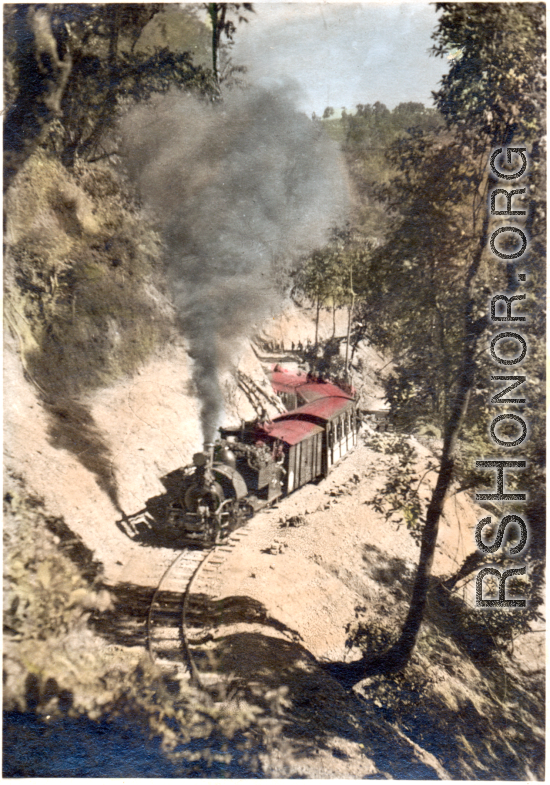 A Darjeeling Himalayan Railway (DHR) B Class 2 ft. saddle tank steam locomotive and train cars climbing the mountain. Hand-tinted image.