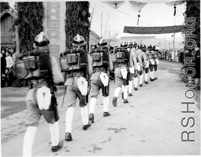 Burma Road dedication parade and ceremony in Kunming, China, on or around February 4, 1945, during WWII. Review of first convoy (or one of the first convoys) to reach China. Chinese soldiers marching in fancy parade dress taking part in elaborate parade.