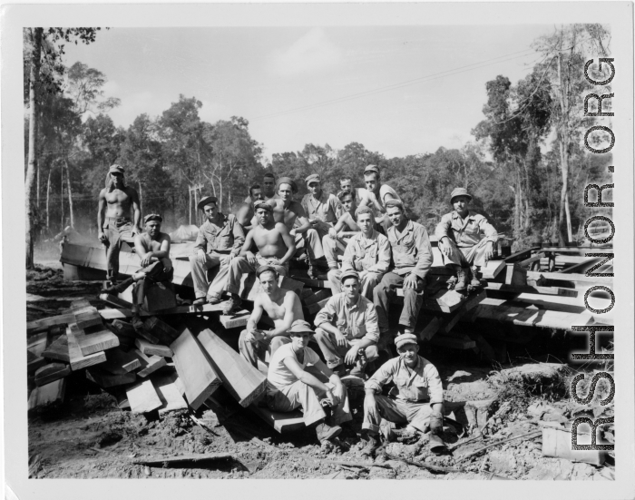 Engineers of the 797th Engineer Forestry Company pose outside on pile of sawn lumber at a camp in Burma.  During WWII.