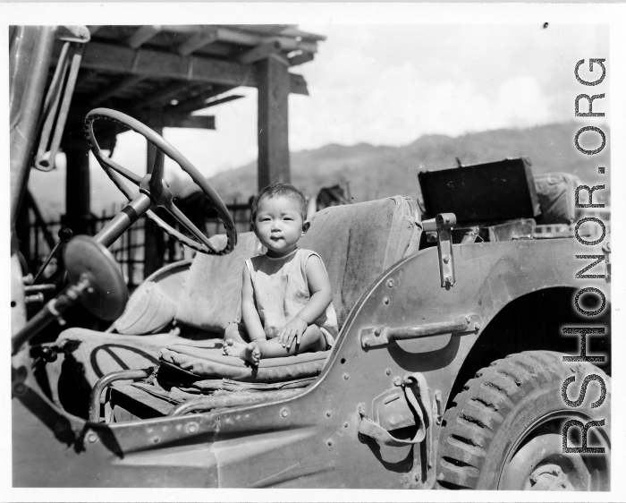 Kid sits in jeep in Burma.  Near the 797th Engineer Forestry Company.  During WWII.