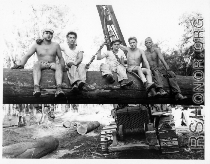 Engineers of the 797th Engineer Forestry Company pose on a log hoisted into the air by a tracked loader.  During WWII.