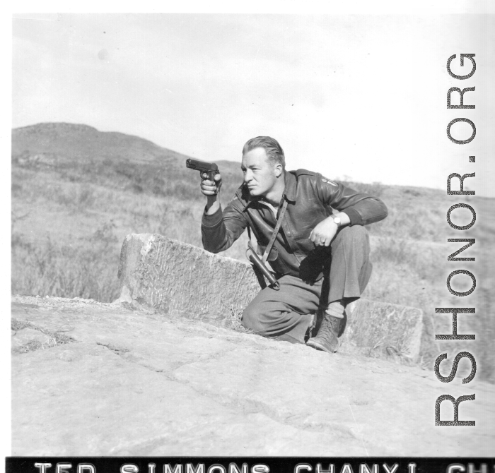 Flyer Ted Simmons playing with pistol on stone bridge at Chanyi (Zhanyi), during WWII.