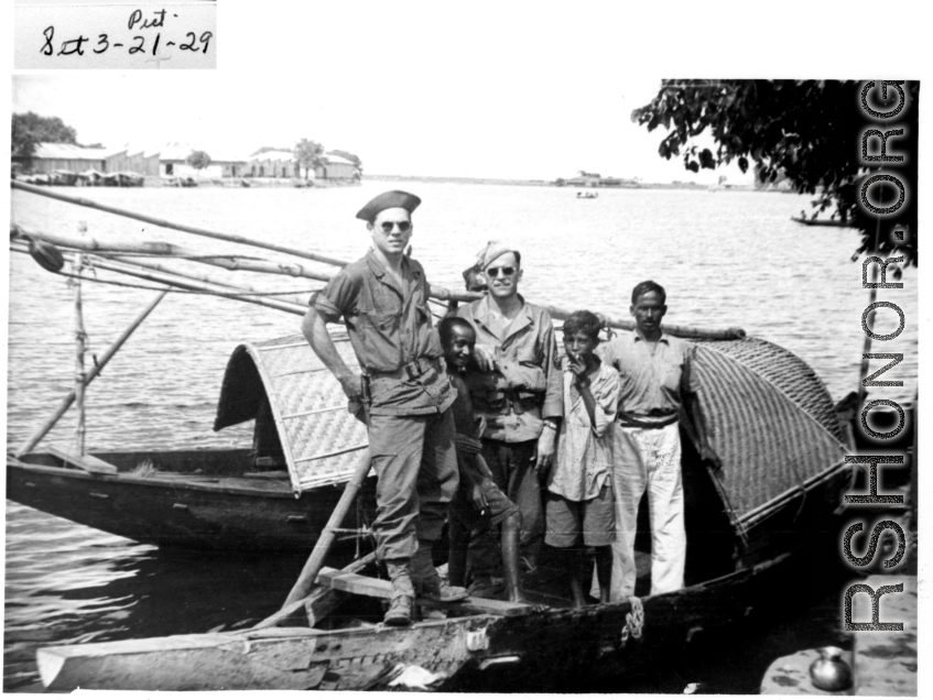 Two GIs on a boat with a family in India or Burma. During WWII.