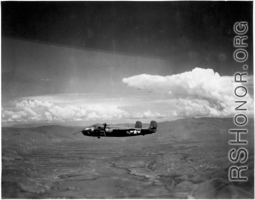 A 491st Bomb Squadron B-25H, tail #439, in formation flight somewhere over China. Look carefully above the tail to see two more B-25s just below the large cloud.