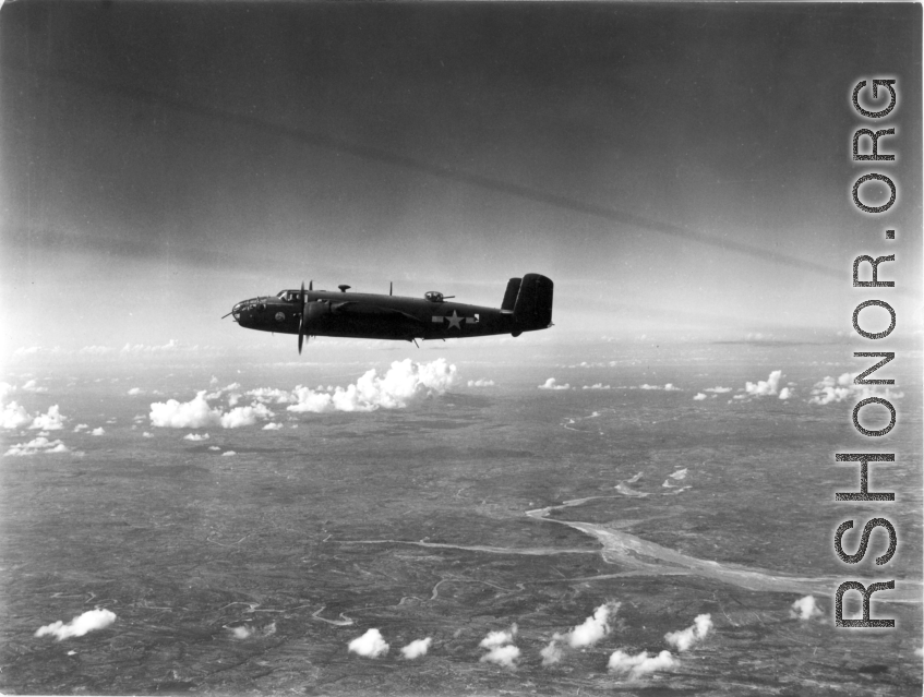 A B-25 Mitchell bomber in flight in the CBI, in the area of southern China, Indochina, or Burma, during WWII.