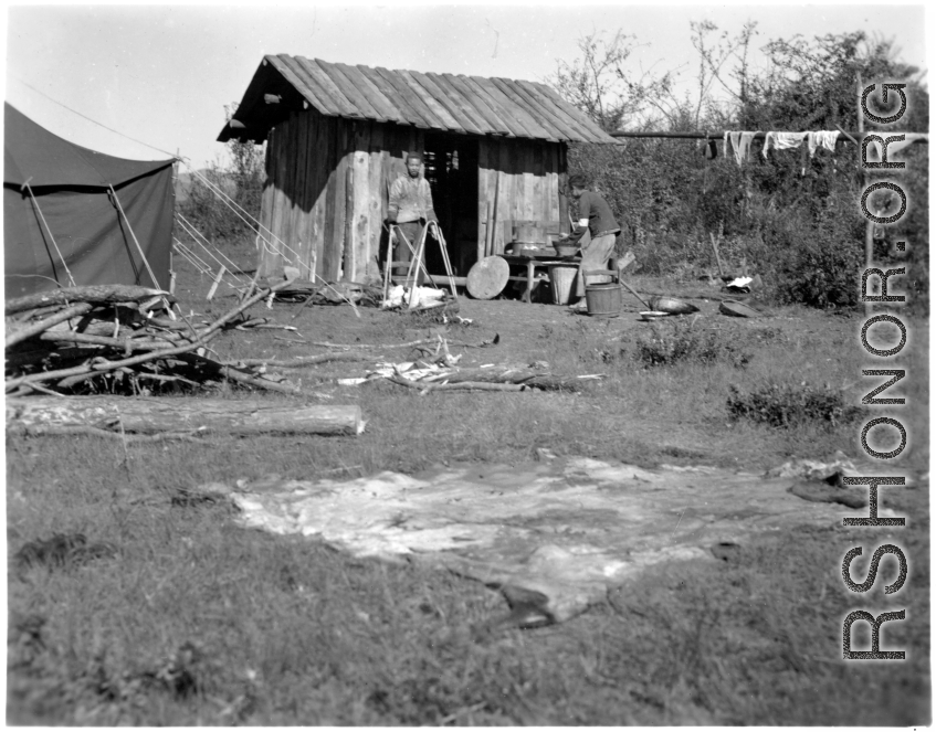 Local people in China: Men prepare to cook rice in a small shack next to American GI tents.  From the collection of Eugene T. Wozniak.