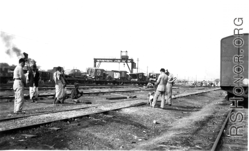 Local people in a train yard in India during WWII. Notice the first aid trucks on flat cars in the background.  From the collection of Eugene T. Wozniak.