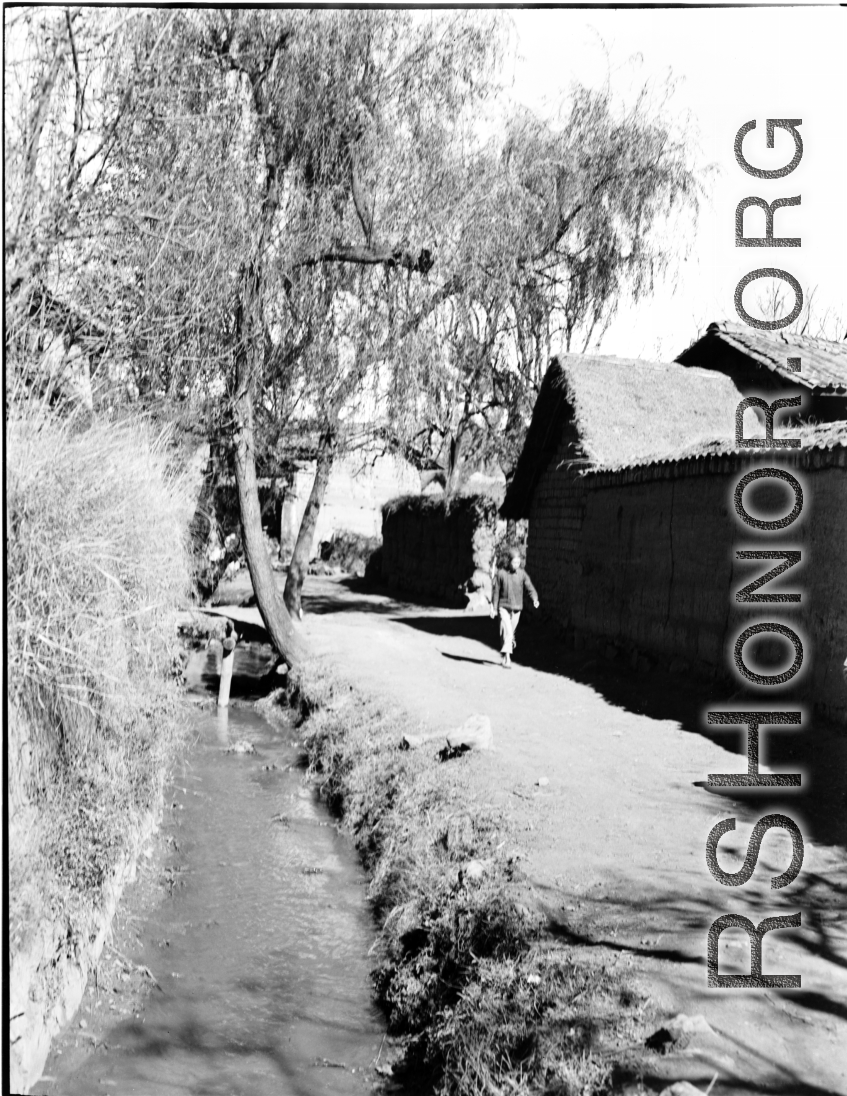Local people in China: A youth walks a path through a village during WWII.