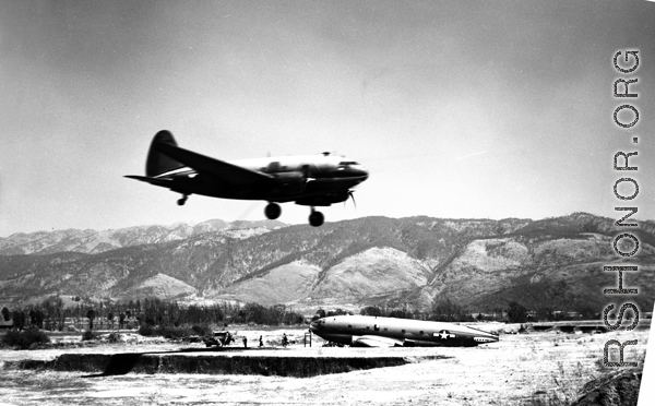 A C-46 lands in Yunnan province, flying in over the carcass of another C-46.