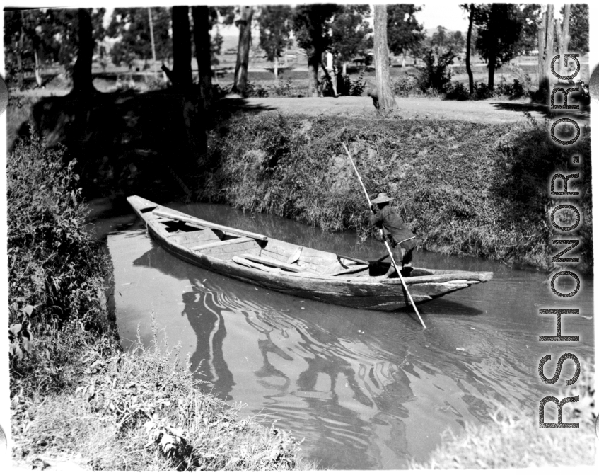 A man poles a small boat on a canal in Kunming, Yunnan province.  From the collection of Eugene T. Wozniak.