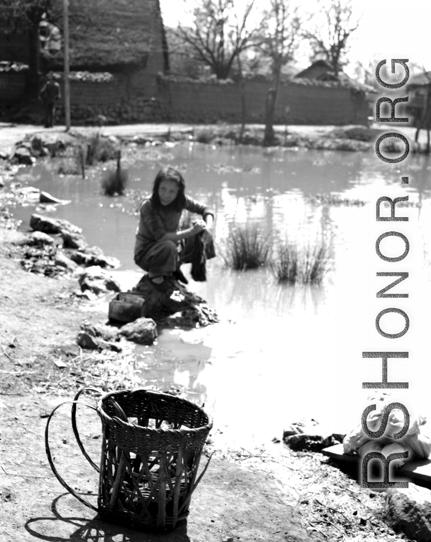 Local people in Yunnan province, China: A woman washes cloth in a village pond. During WWII.  From the collection of Eugene T. Wozniak.