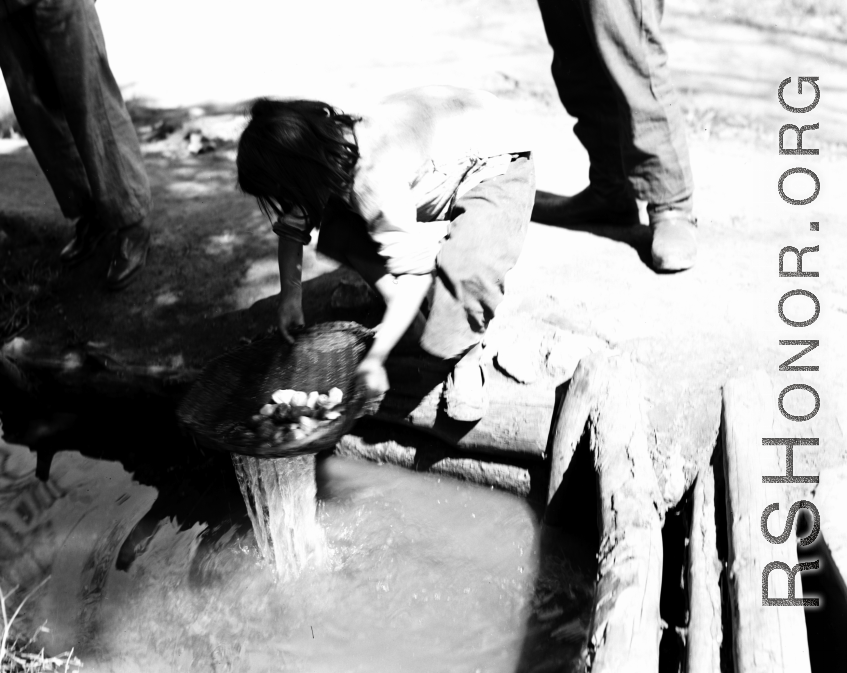 Local people in China: Woman washes some kind of produce in a water channel, during WWII.  From the collection of Eugene T. Wozniak.