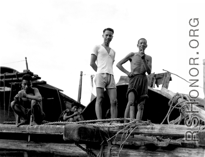 Chinese men on a wooden structure give a curious smile for the photographer, China.  From the collection of Wozniak, combat photographer for the 491st Bomb Squadron, in the CBI.