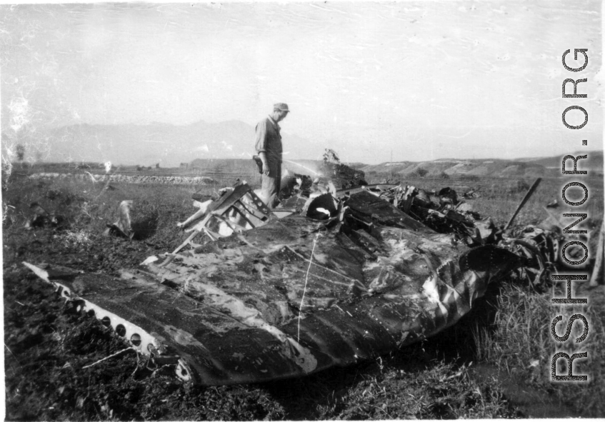 A GI examines the wing of a crashed aircraft in the CBI during WWII.