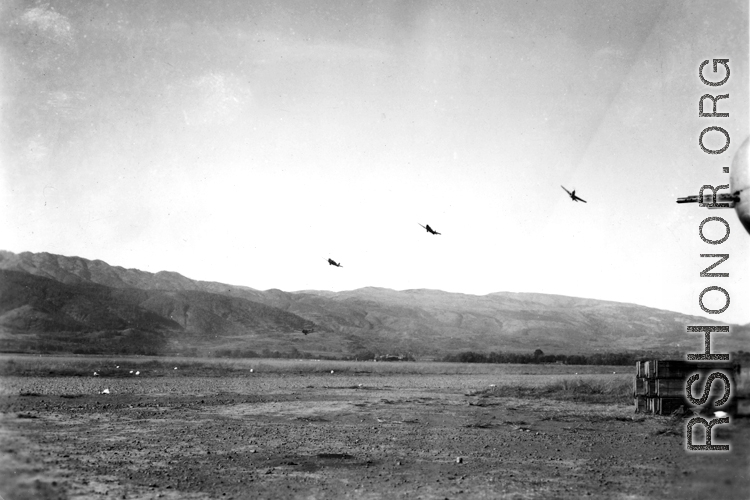 Several P-40 fighters pass over the runway and begin a "break out" to land at Yangkai, Yunnan province. The nose guns of an American B-25H bomber are visible at the far right of this picture taken in the CBI.