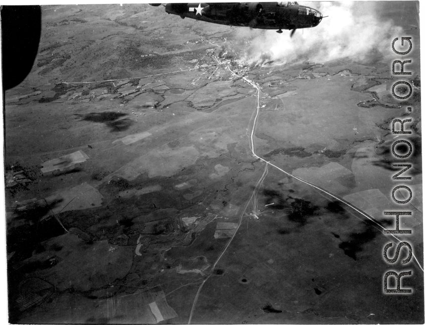 Smoke rises on the ground at a crossroads of the Burma Road after an attack by American B-25s in either SW China, Indochina, or the Burma area.  This might be fairly close to Tengchong in China.