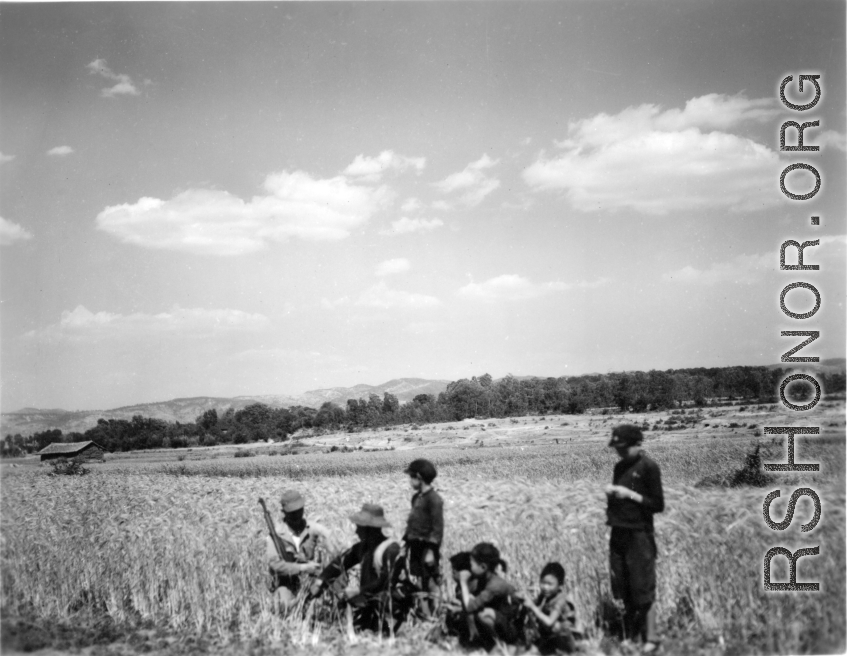 Local people in Yunnan province, China: An American GI chats with a farmer and kids at harvest time, with the grain fields ripe and ready, during WWII.