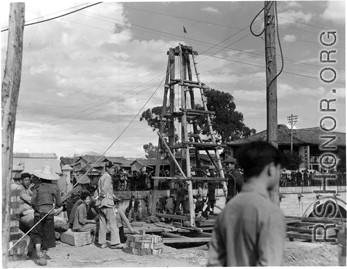 Local people in Yunnan, China: A construction site, using a small wooden derrick to drive in piles or dig a well. During WWII.