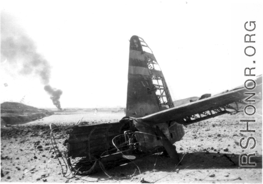 An American airplane destroyed after a Japanese air raid, with another burning in the distance. In China, during WWII.