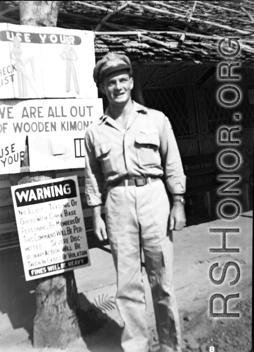 A GI stands before signs on a base in China during WWII.