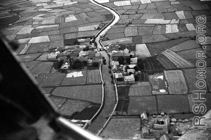 A tidy village near Kunming, as seen from the air, during WWII, with a canal passing through the village.