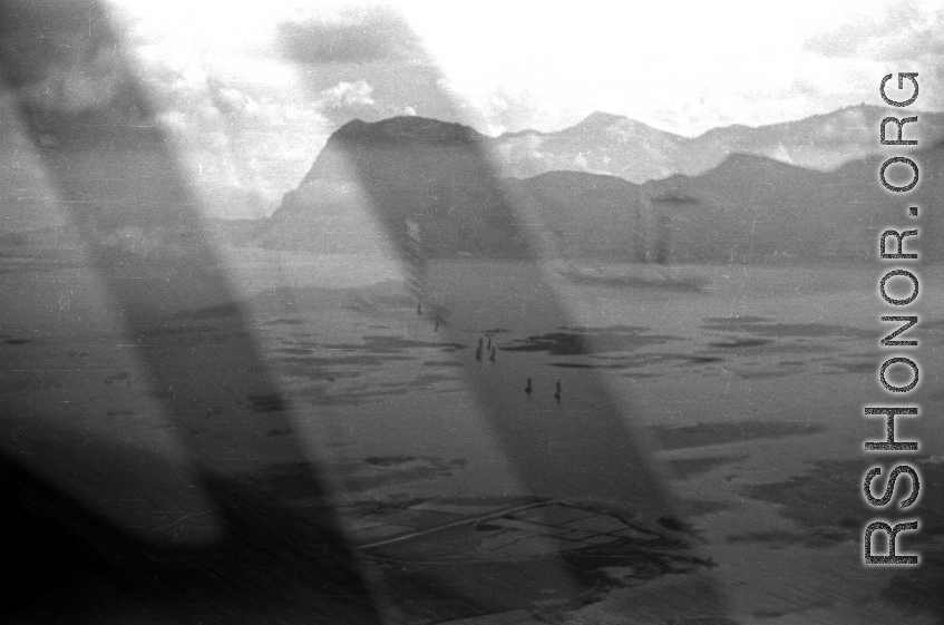 View over Dianchi Lake (滇池) outside of Kunming, China, during WWII. Small boats with sails move in a line on the water surface. 