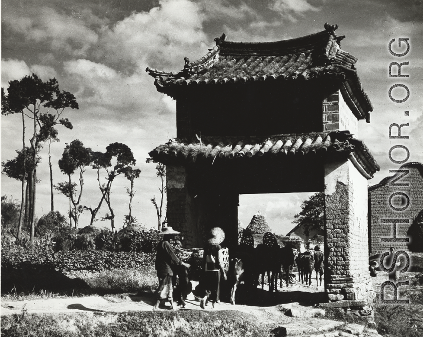 Farm folk go through a gate-like structure near Kunming, in Yunnan province. During WWII.