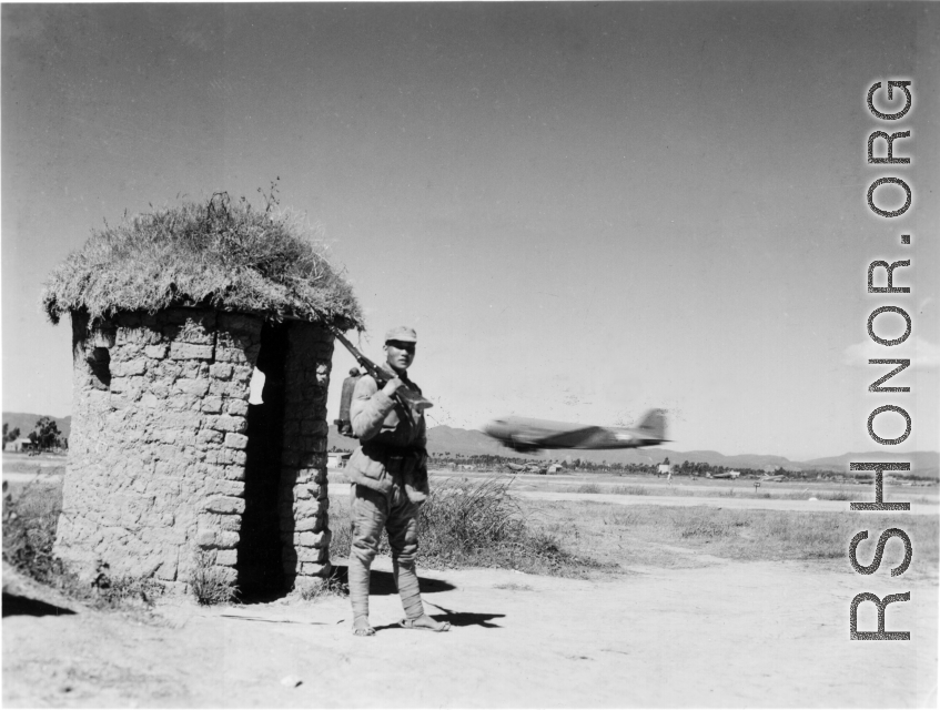 An American C-47 takes off behind a Chinese base guard in SW China during WWII.