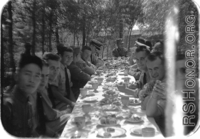 SACO members share a meal with Nationalist soldiers, in the shade of trees, during WWII. In northern China.