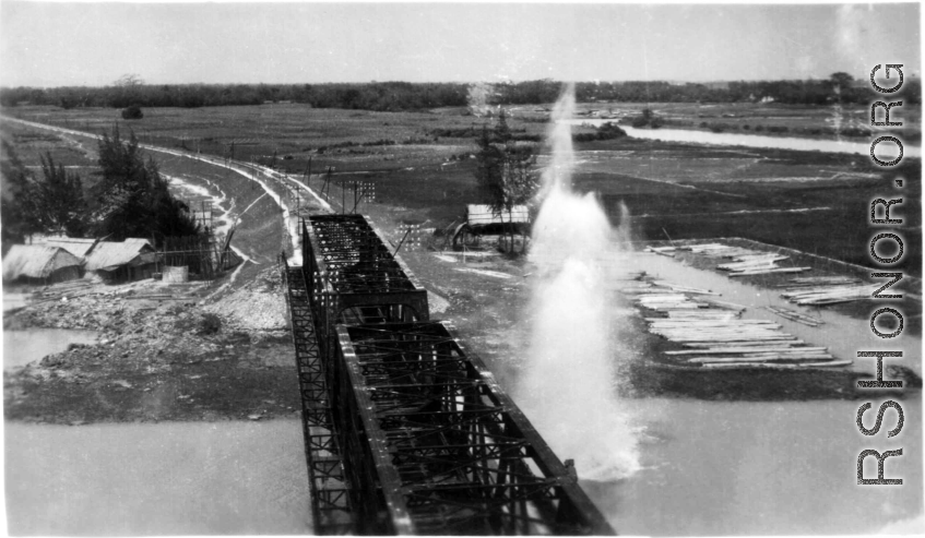An aerial photograph of a railway bridge being bombed--a near miss--by the 491st Bomb Squadron in Yunnan or Indochina, during WWII.
