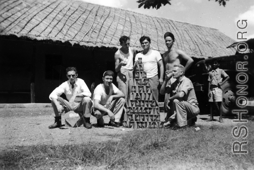 GIs with beer can pyramid during WWII.  Americans in the CBI. Probably India.