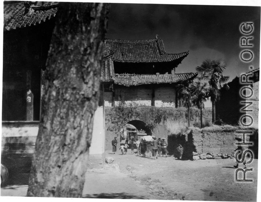 A village gate, with a temple to left with “太平乐事” written above door. During WWII.