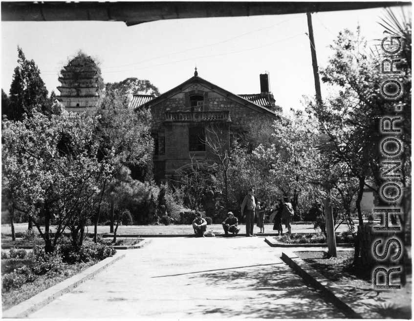 Americans and Chinese on an administrative (ie, university or similar) or a housing compound, with a Buddhist pagoda in the background--indication that the grounds were once a Buddhist temple, later appropriated and converted during Nationalist social movements.
