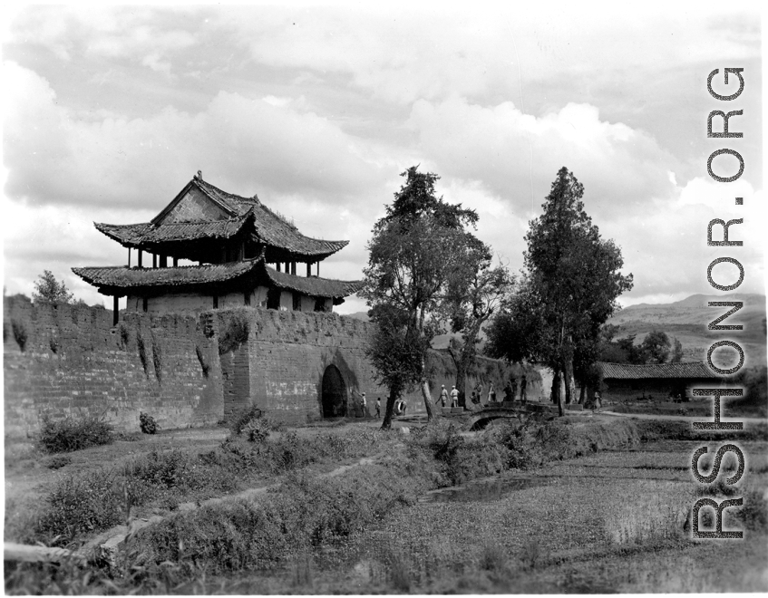 A city wall with gate (probably at Chengkung/Chenggong) and local people in Yunnan province, China.
