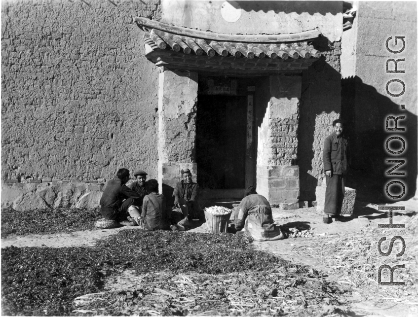 Local people in Yunnan province, China, chatting, sorting pea pods, or waiting as greens dry in the sun. During WWII.