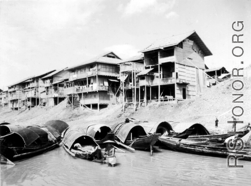 Waterside houses in China, with boats floating in the foreground, during WWII.