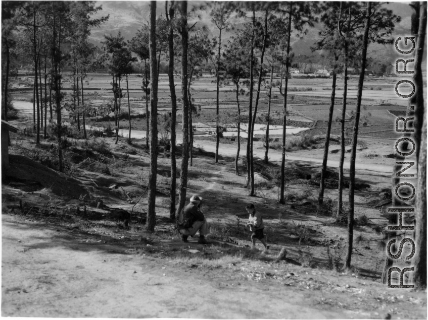 GI explorations of the hostel area at Yangkai air base during WWII: A GI interacts with a child in a pine grove.
