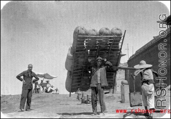Man shoulders sheep-skin raft in northern China during WWII.