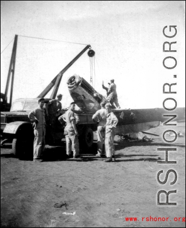 12th Air Service Group mechanics salvage a P-51 fighter in Guangxi, China, during WWII, cranking the aircraft up onto a flatbed truck.