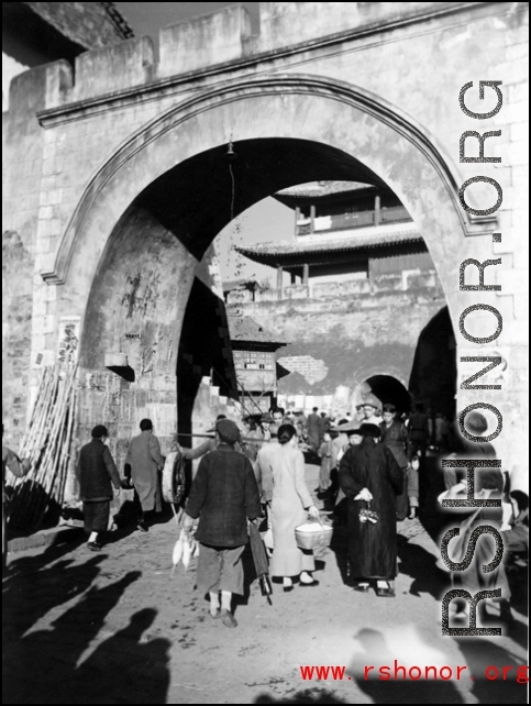 Civilians come and go at a gate in a city wall in China during WWII.