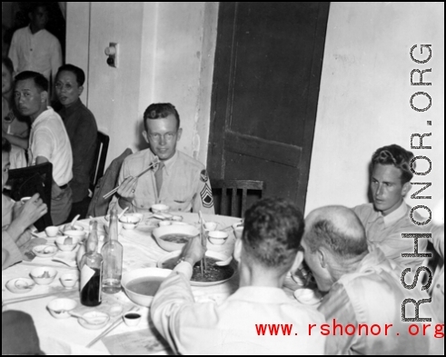 16th Combat Camera Unit members enjoy a banquet in China during WWII. Hal Geer holds up a jiaozi (饺子) in his chopsticks as he looks at the camera.