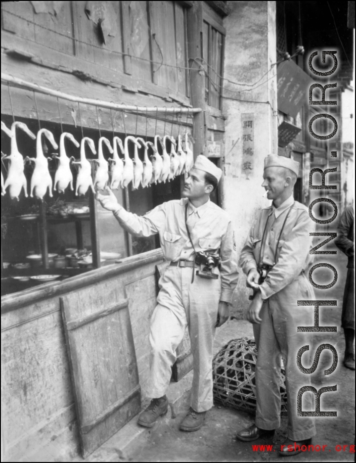 16th Combat Camera Unit photographer Selig Seidler and another man inspect ducks at a restaurant in China during WWII.