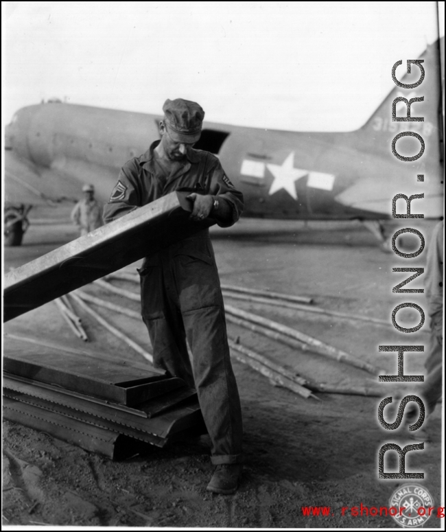 American GI working on air supply with C-47 in the background, and a Chinese worker standing nearby.