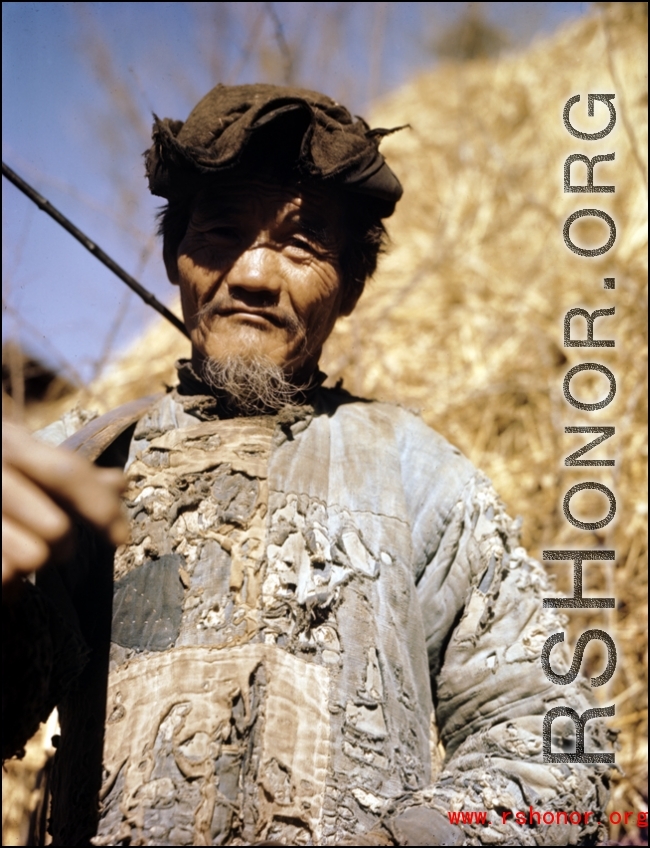 A tattered farmer with a shoulder pole in Yunnan province, China. During WWII.