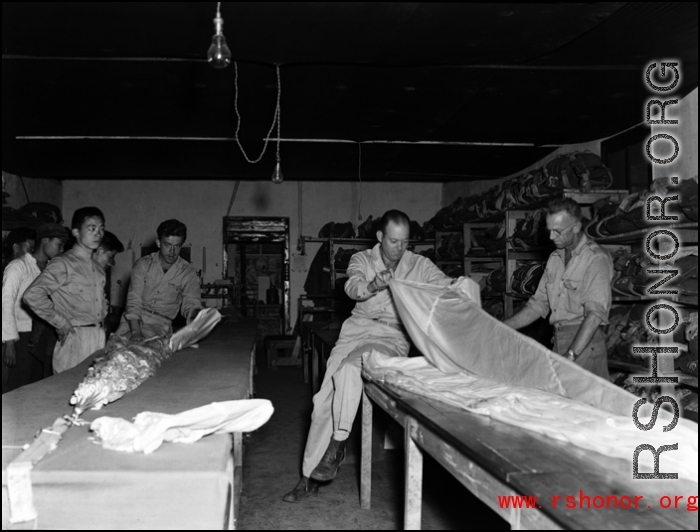 Packing and checking parachutes--a truly vital and exacting task. At an American base, China, during WWII.