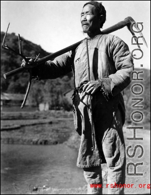 Local people in China, probably in Yunnan province: A farmer shouldering his tools.  From the collection of Wozniak, combat photographer for the 491st Bomb Squadron, in the CBI.
